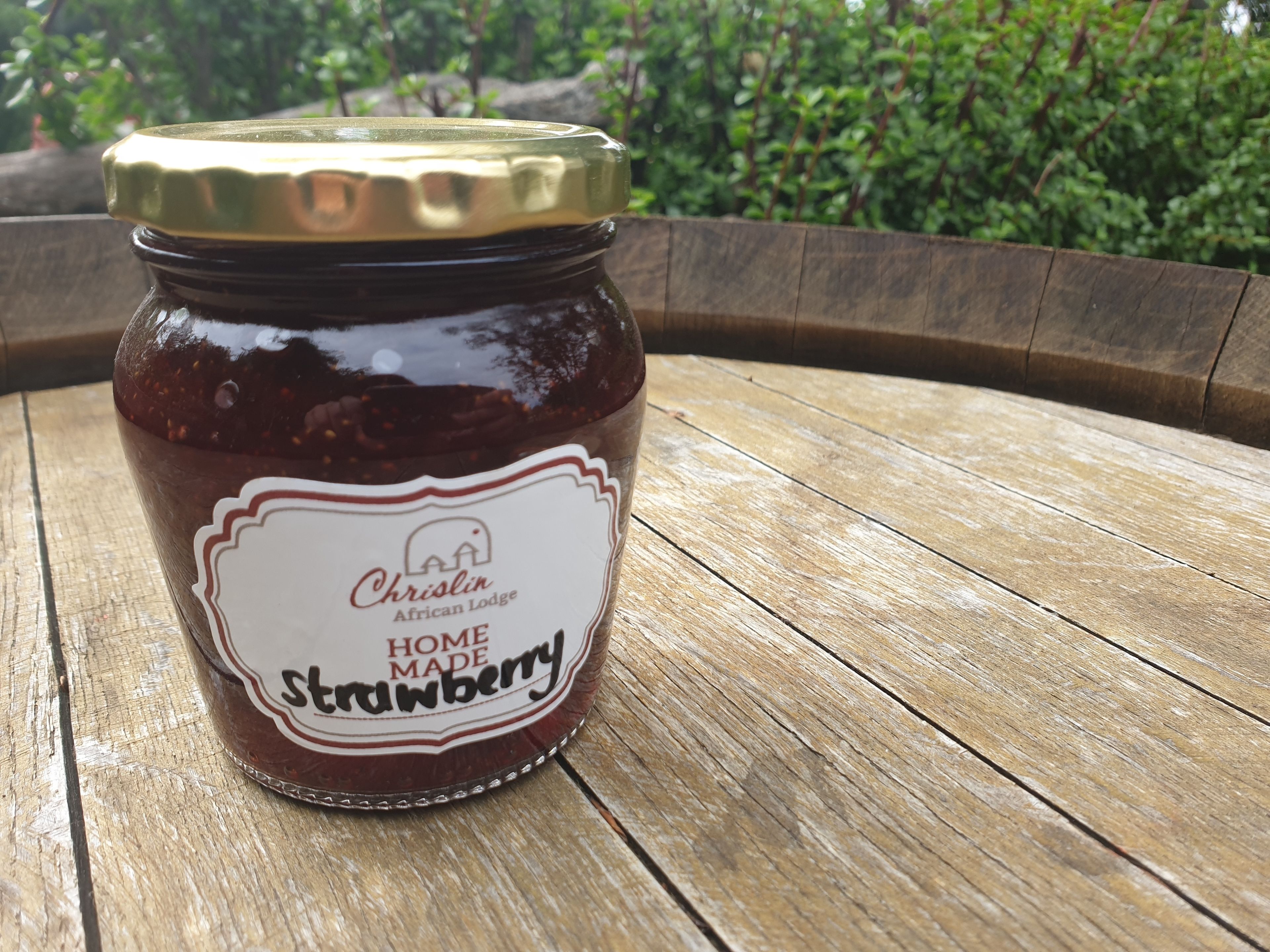 Un bocal de confiture de fraises maison sur une table en bois.