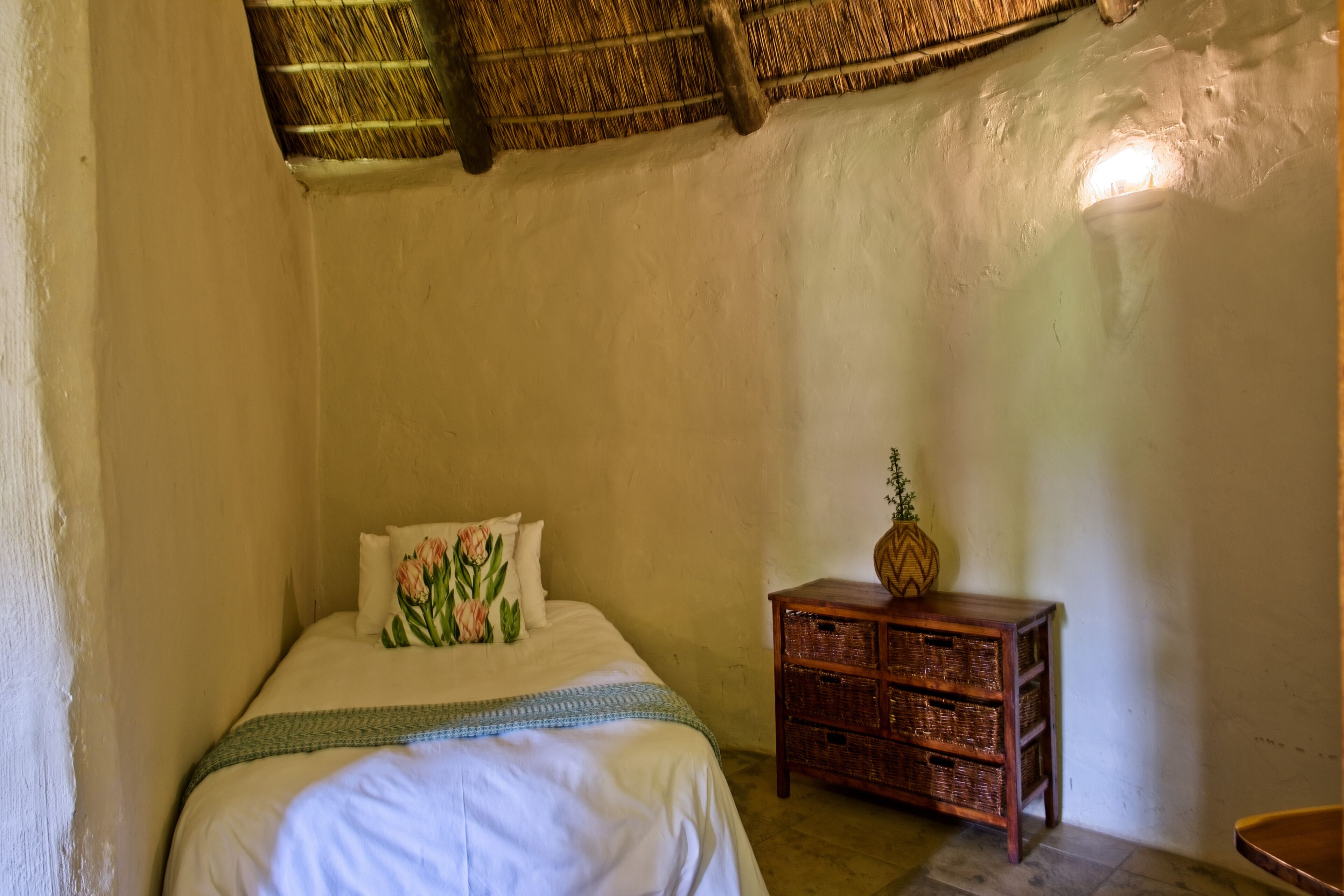 A bedroom with a bed, a nightstand, and a wicker basket.