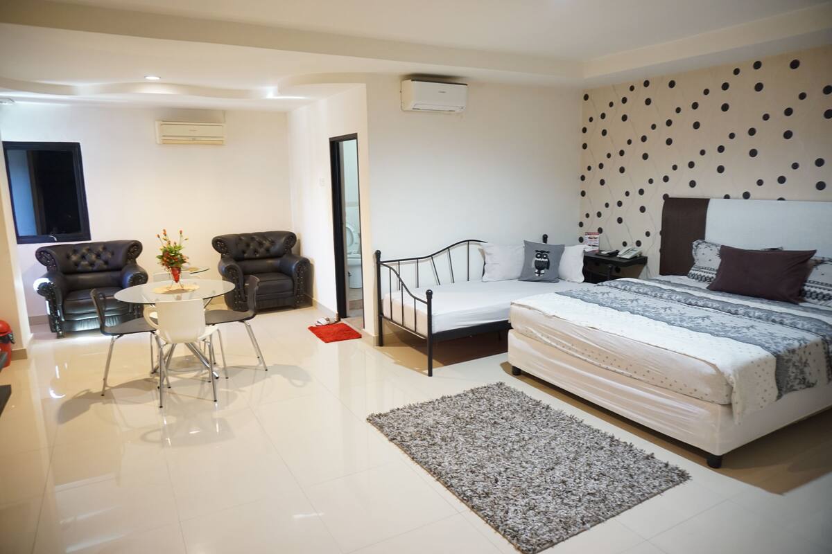 Une chambre moderne avec un lit, une table de chevet et une petite table accompagnée de chaises.