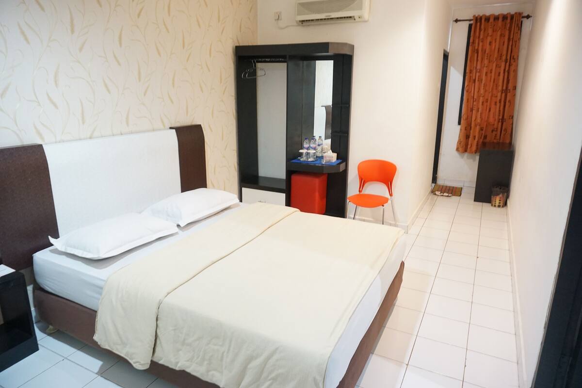 Une chambre d’hôtel comprenant un lit, un bureau, une chaise, un miroir et une armoire.