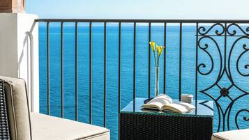 Un balcón con muebles de mimbre, una planta en maceta y vista al mar.