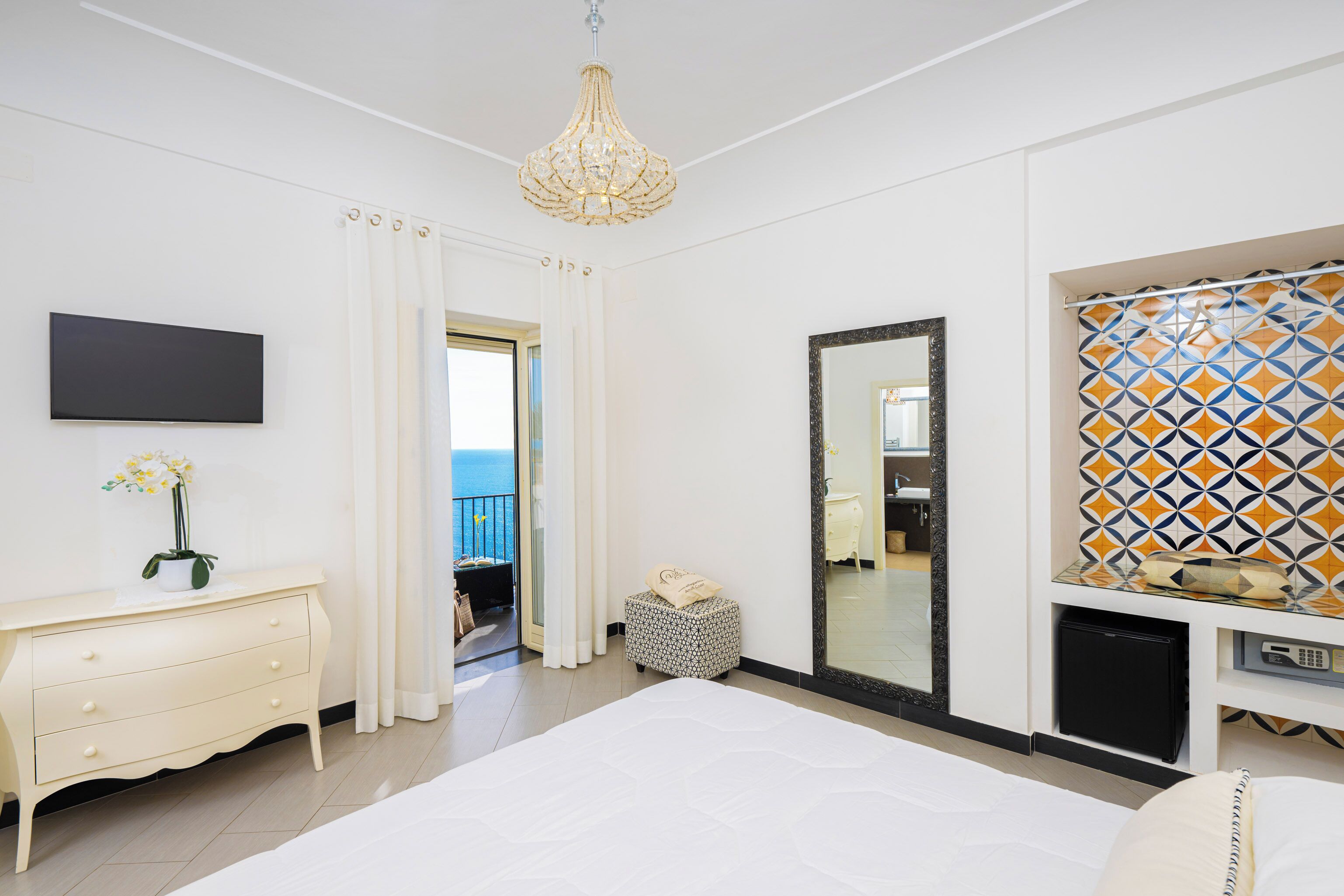 A bedroom with a bed, a dresser, a mirror, and a television.