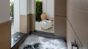 Un baño moderno con una bañera grande, cabina de ducha de vidrio y vistas a un jardín.