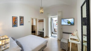 Una habitación de hotel con cama, escritorio, televisor y un espejo grande.