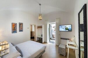 Una habitación de hotel con cama, escritorio, televisor y un espejo grande.