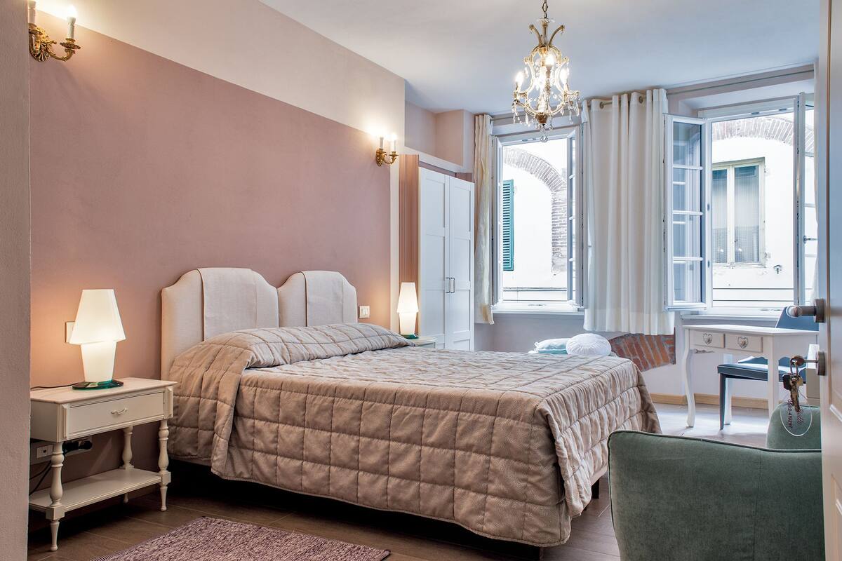A bedroom with a bed, bedside tables, a desk, and a chair.