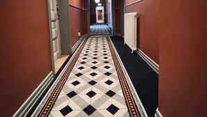 A hallway with a patterned floor, red walls, and a door at the end. - Stationen Bed & Breakfast (Ystad)