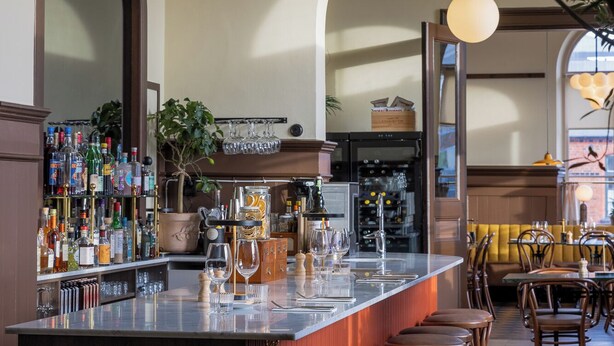 A bar area with a long counter, stools, and a variety of bottles and glasses. - Stationen Bed & Breakfast (Ystad)