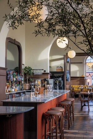 A bar area with a long counter, stools, and a variety of bottles and glasses. - Stationen Bed & Breakfast (Ystad)