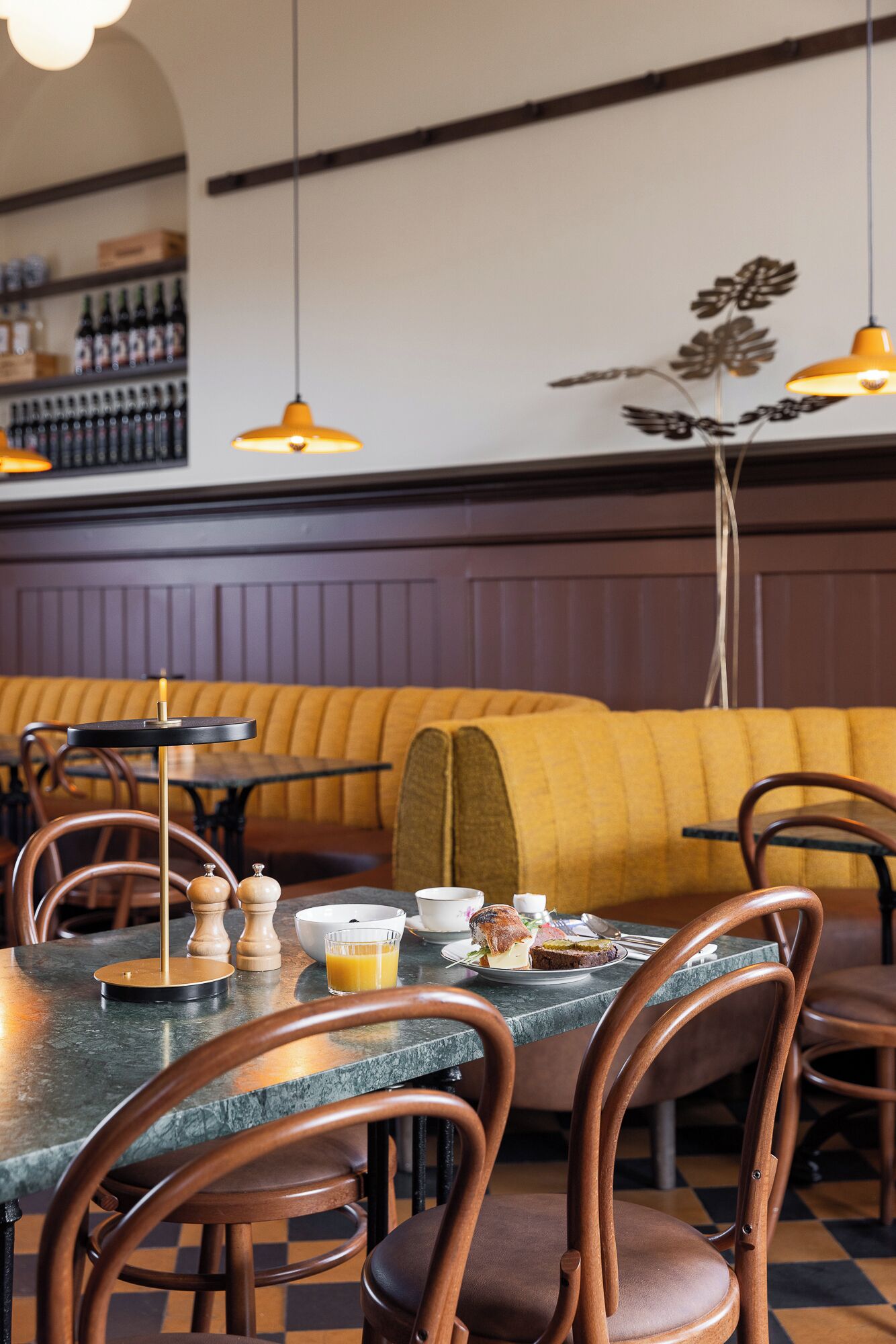 Un interior de restaurante con un largo banco de madera, mesas redondas y sillas.