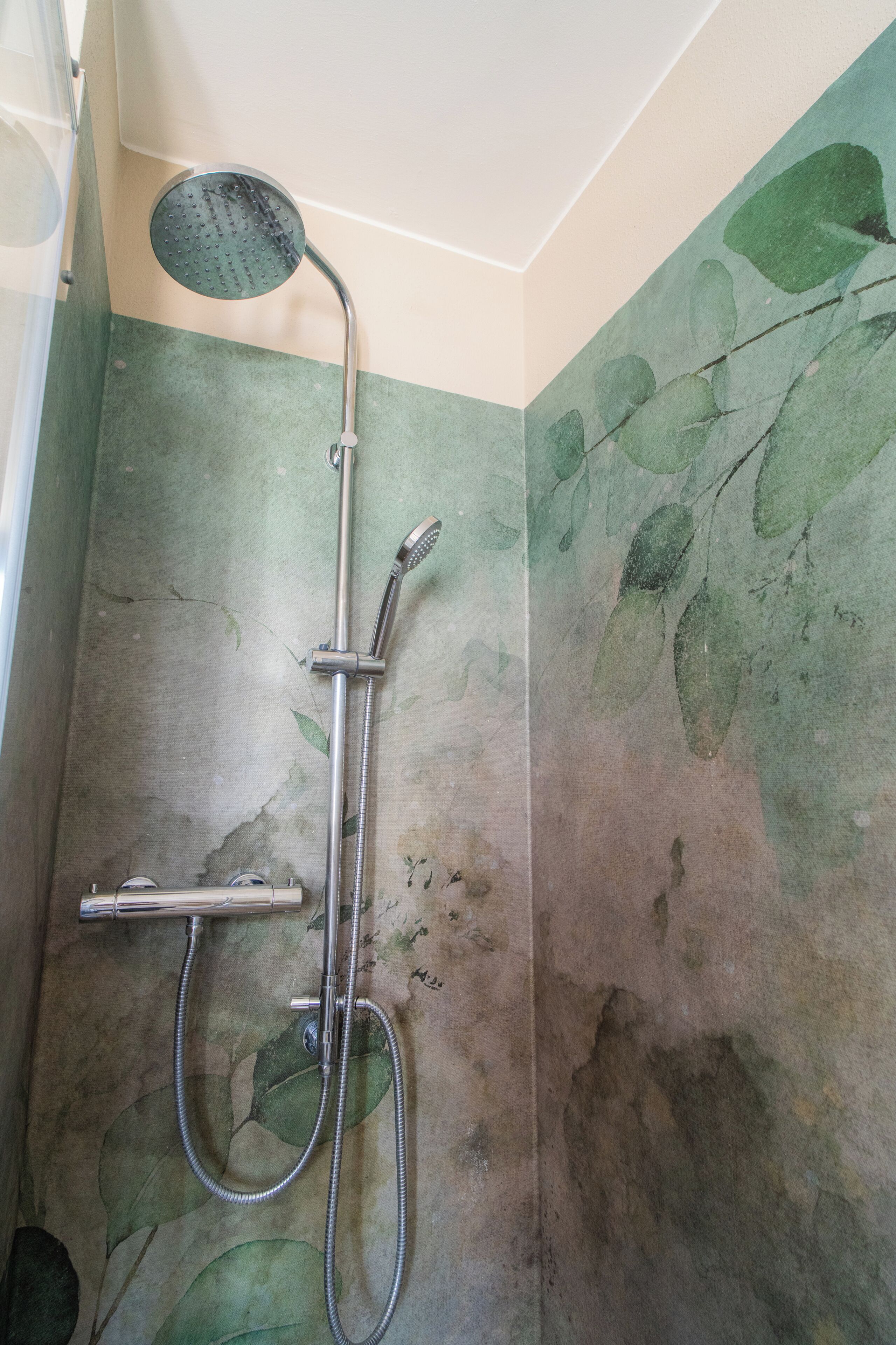 A shower with a handheld showerhead and a handheld faucet.