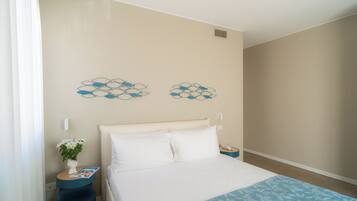 A bedroom with a bed, a nightstand, a vase with flowers, and wall art.