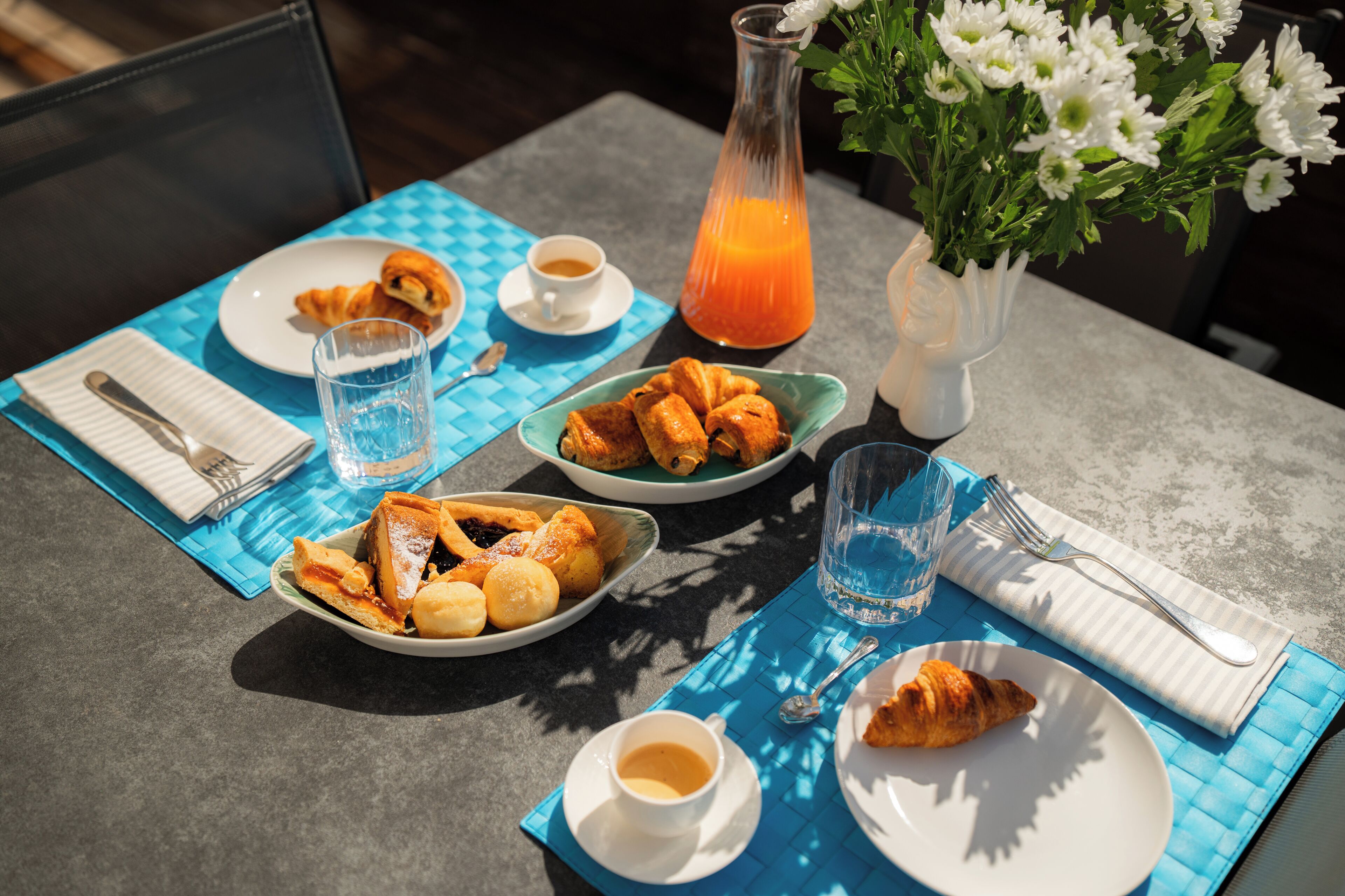 Una tavola apparecchiata per la colazione, con croissant, dolci e un bicchiere di succo d'arancia.