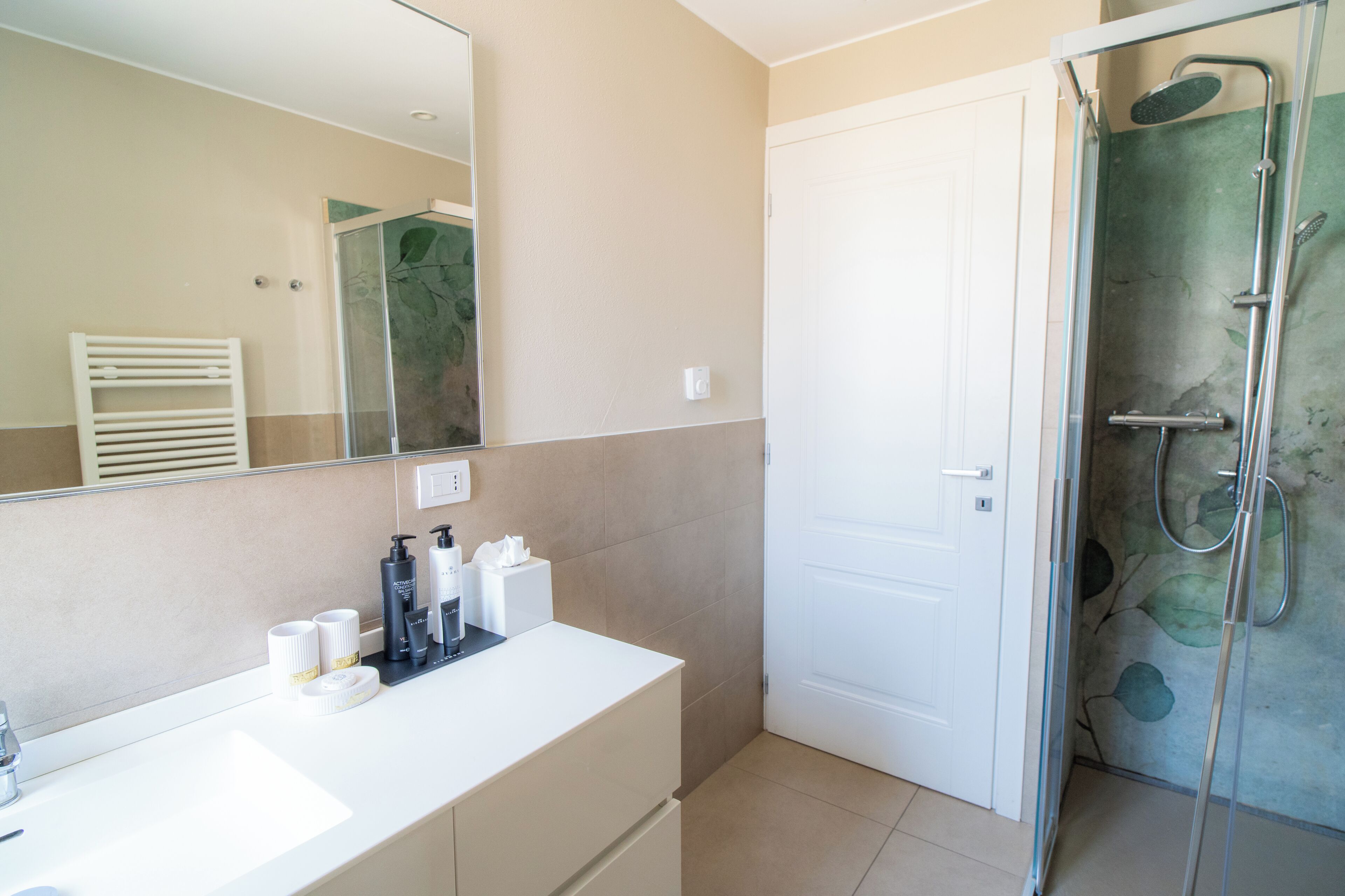 A bathroom with a white sink, mirror, and shower.