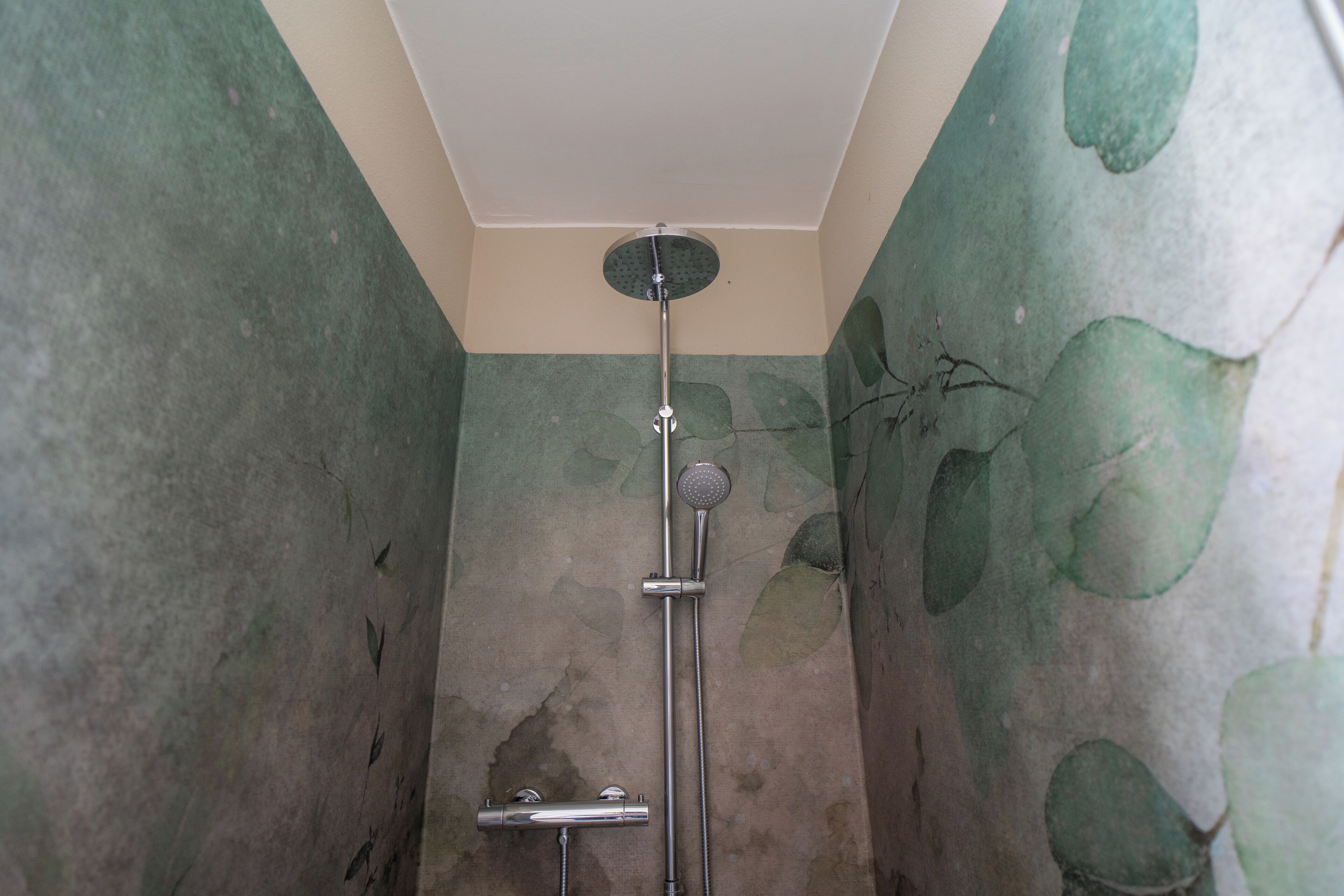 A shower with a handheld showerhead and a wall-mounted faucet.