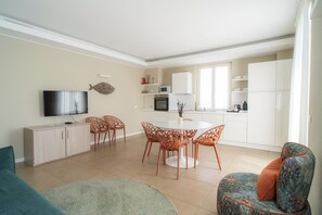 A modern living room with a TV, sofa, and dining area with chairs and a table.