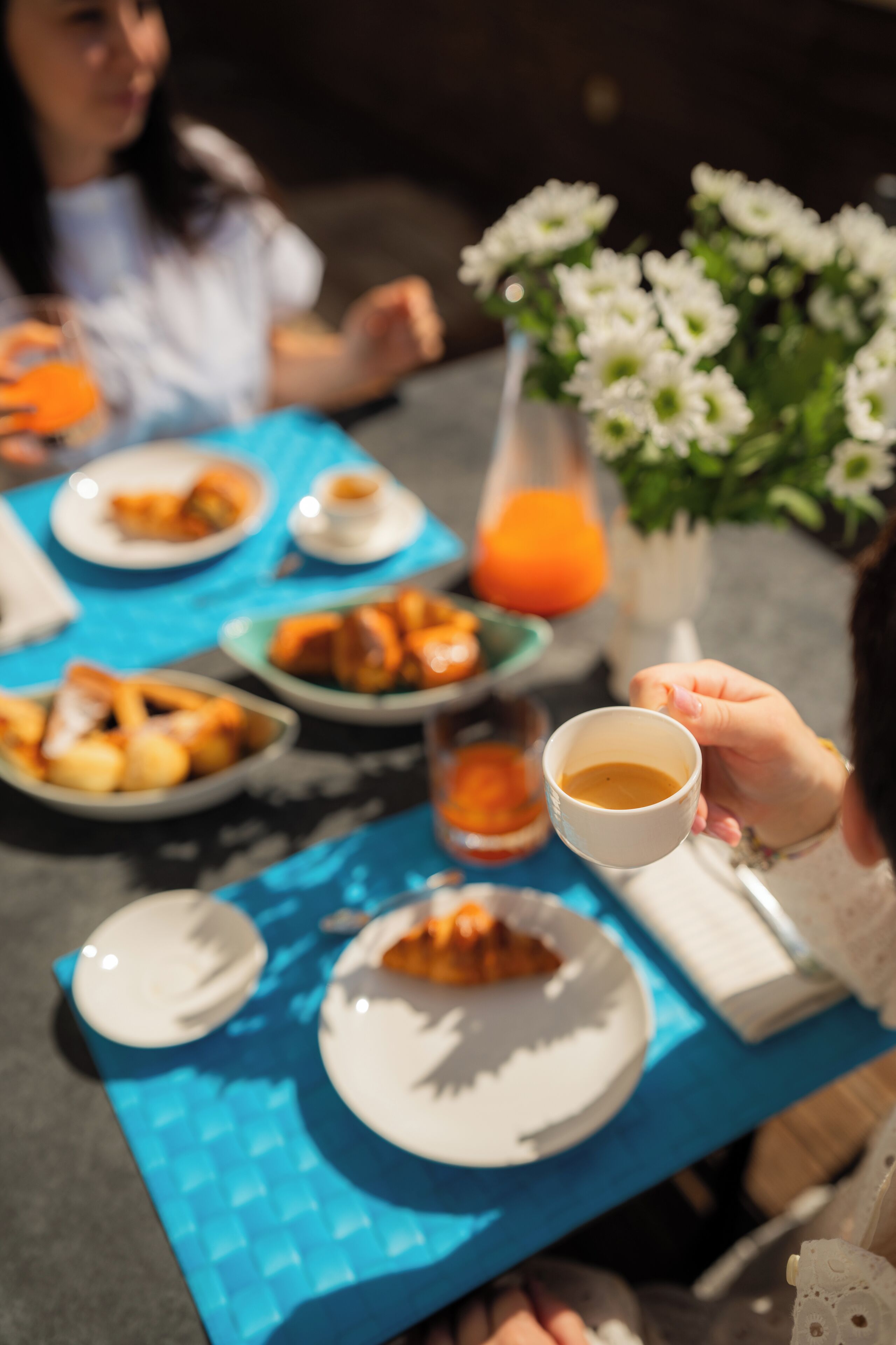 Un tavolo imbandito con piatti di cibo, una tazza di caffè e un vaso di fiori.