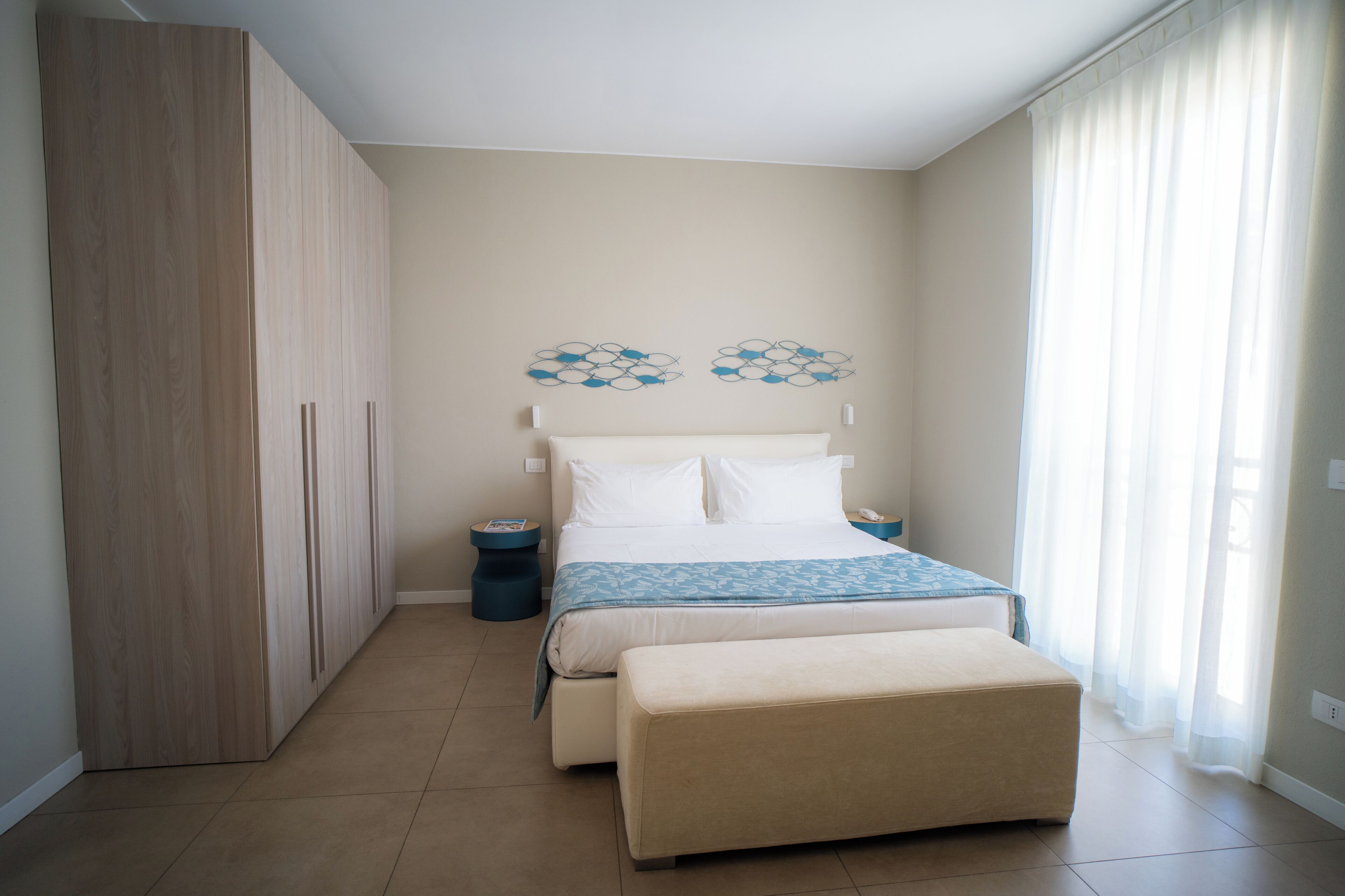 Une chambre à coucher avec un lit, des tables de chevet, une armoire et une fenêtre avec des rideaux.