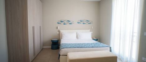 A bedroom with a bed, bedside tables, a wardrobe, and a window with curtains.