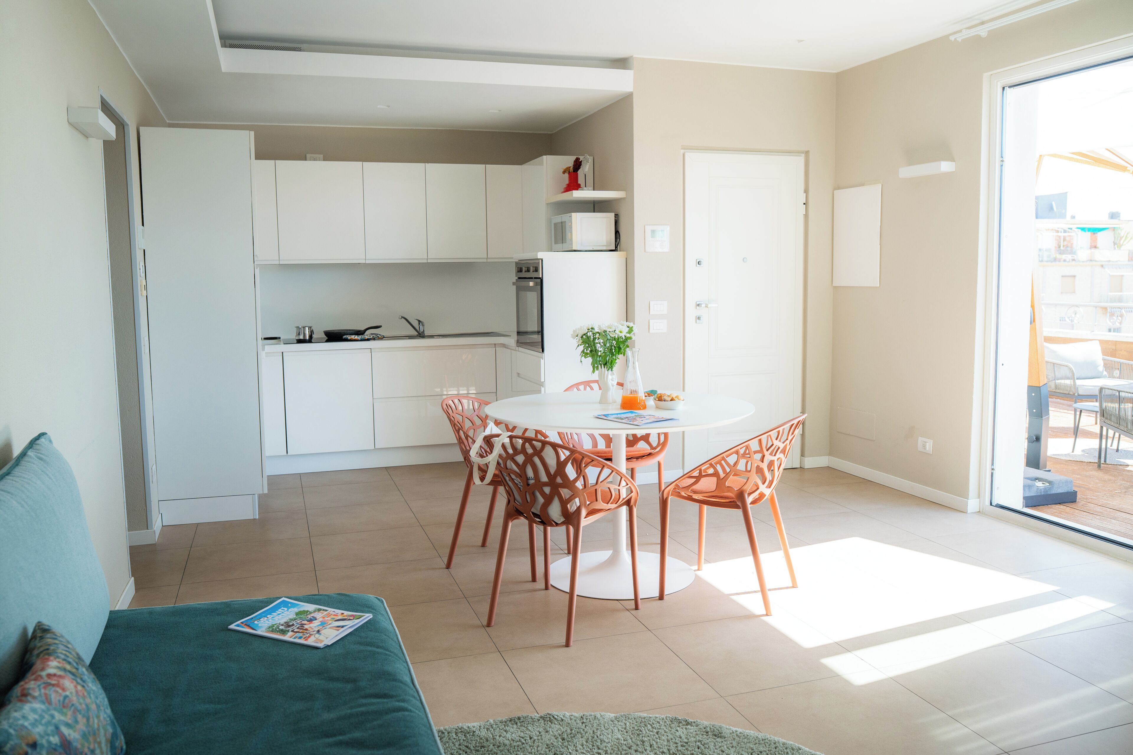 Ett kompakt bostadsutrymme med ett litet kök, en matplats och en skjutdörr i glas som leder ut till en uteplats.