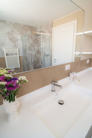 Un bagno con un lavandino bianco, uno specchio e una doccia.