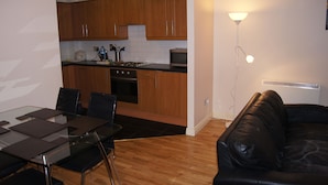 A compact living space with a dining area, kitchenette, and a leather sofa. - Castleforbes Holiday Apartment (Dublin)