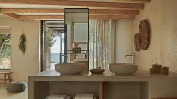 Un baño moderno con un espejo grande, dos lavamanos y vista al mar.