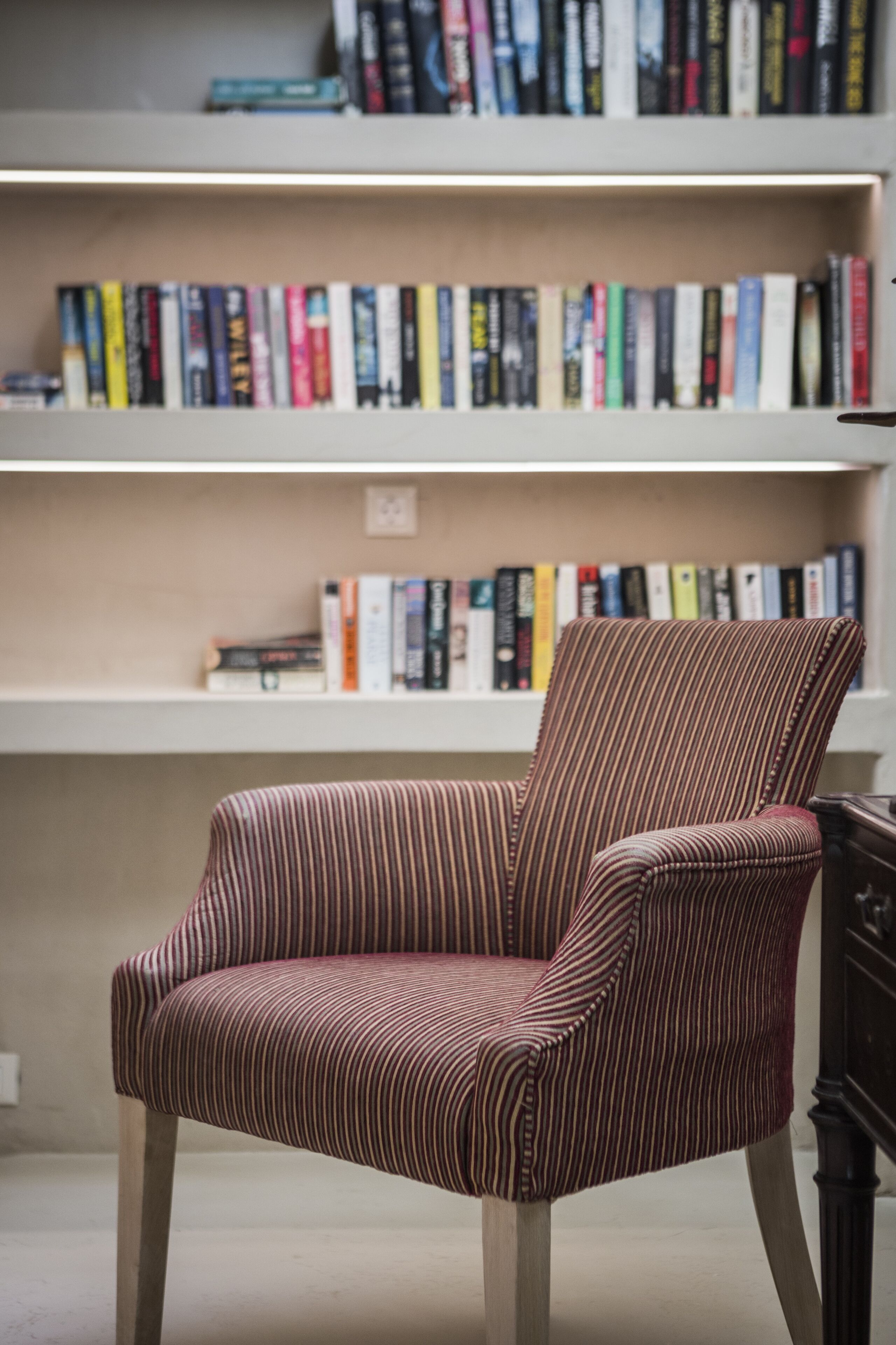 Ein gestreifter Sessel in einem Raum mit einem Bücherregal voller Bücher.