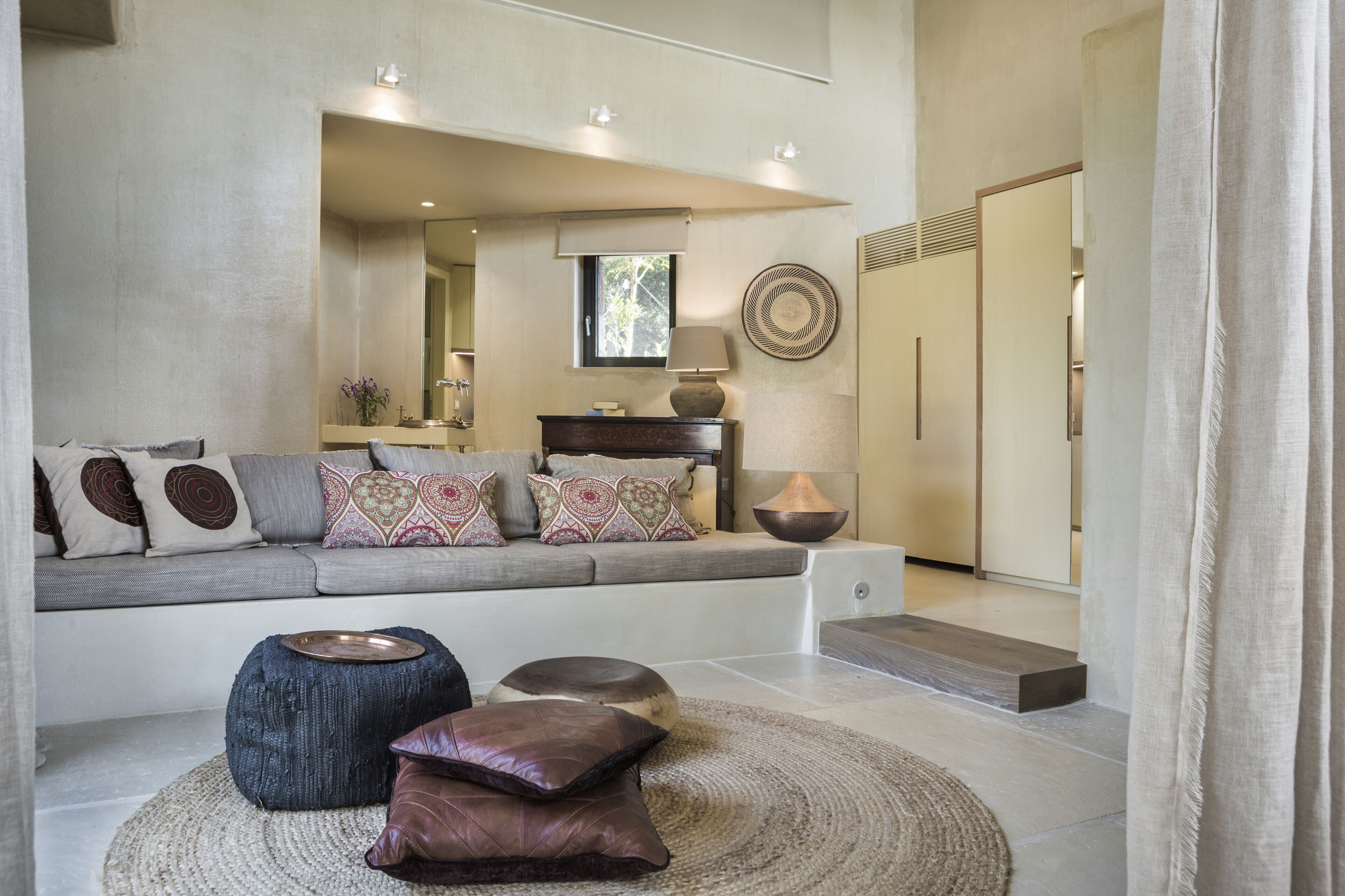 A modern living room with a grey sofa, patterned cushions, a round rug, and a wooden coffee table.