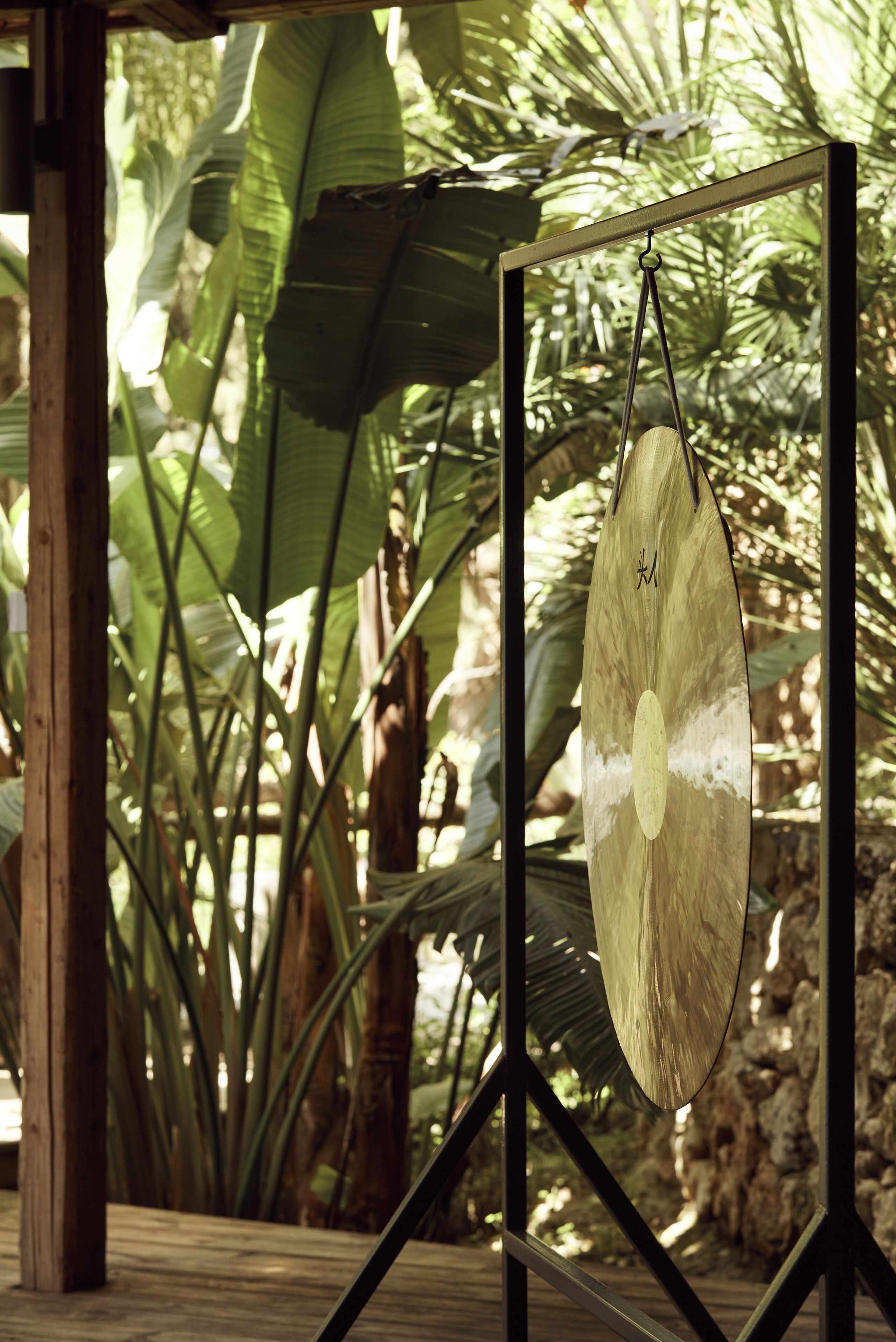 A wooden deck with a hanging wooden board, surrounded by lush green foliage.
