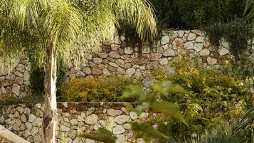 Un jardin où l’on trouve une grande variété de plantes et un mur en pierre.