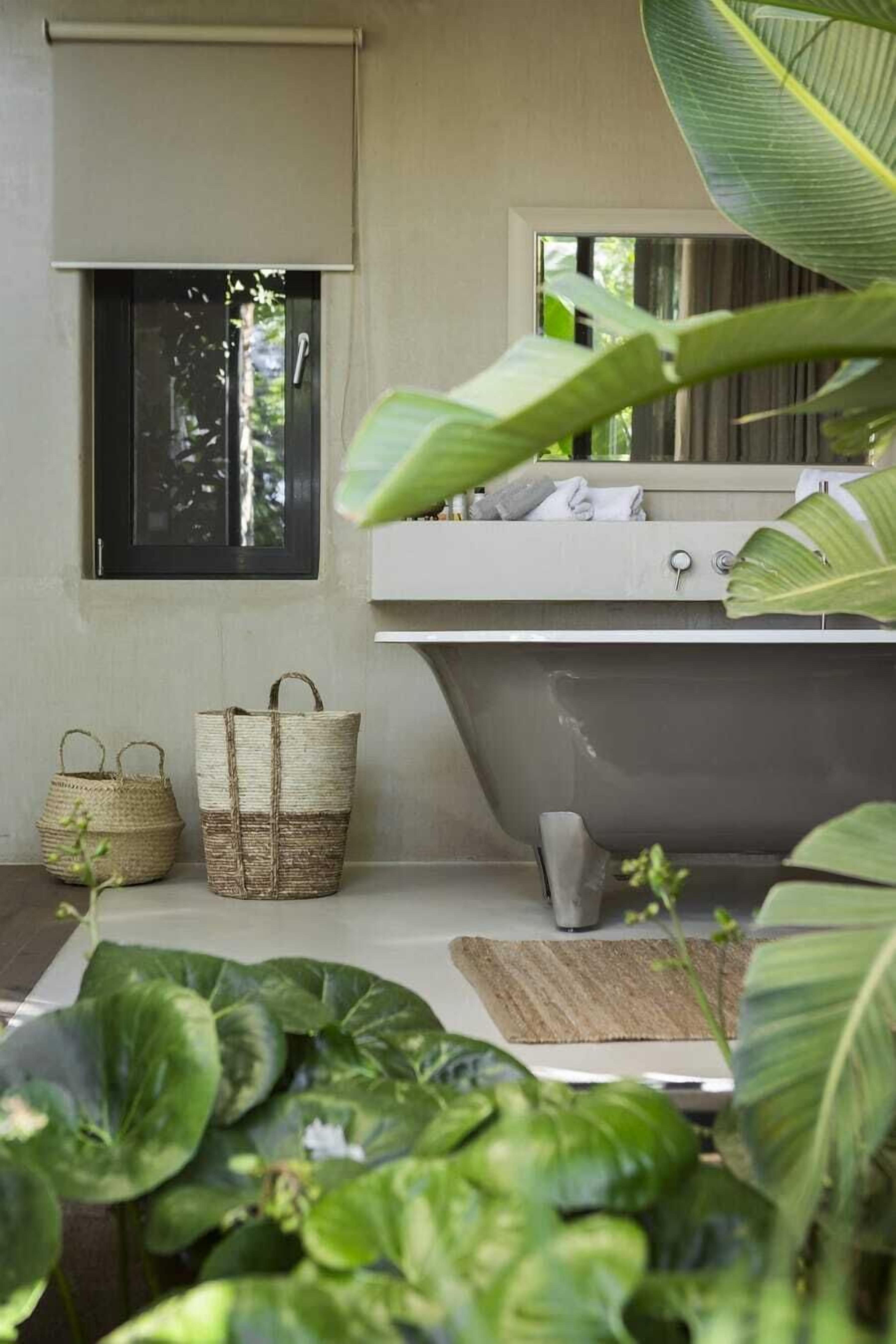 A bathroom with a bathtub, a window, and two woven baskets.