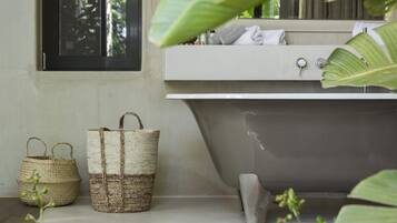 Un baño con una bañera, una ventana y dos cestas tejidas.