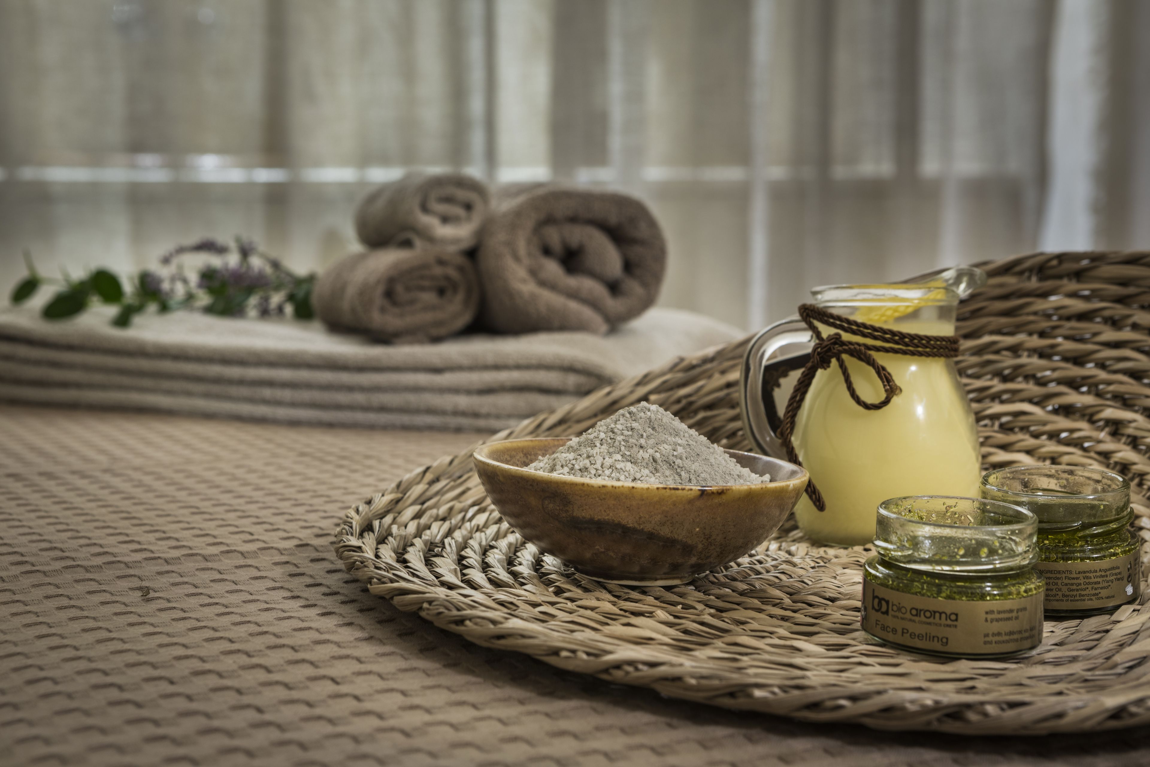 Un plateau en osier contenant un bol de poudre, une bouteille en verre avec une étiquette et deux petits pots également munis d’étiquettes.