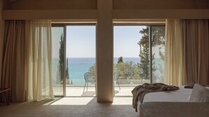 Une chambre dotée d’une grande porte-fenêtre coulissante donnant sur un balcon avec vue sur la mer.