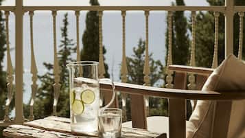 A wooden table with a pitcher and glasses on a balcony overlooking a scenic view.