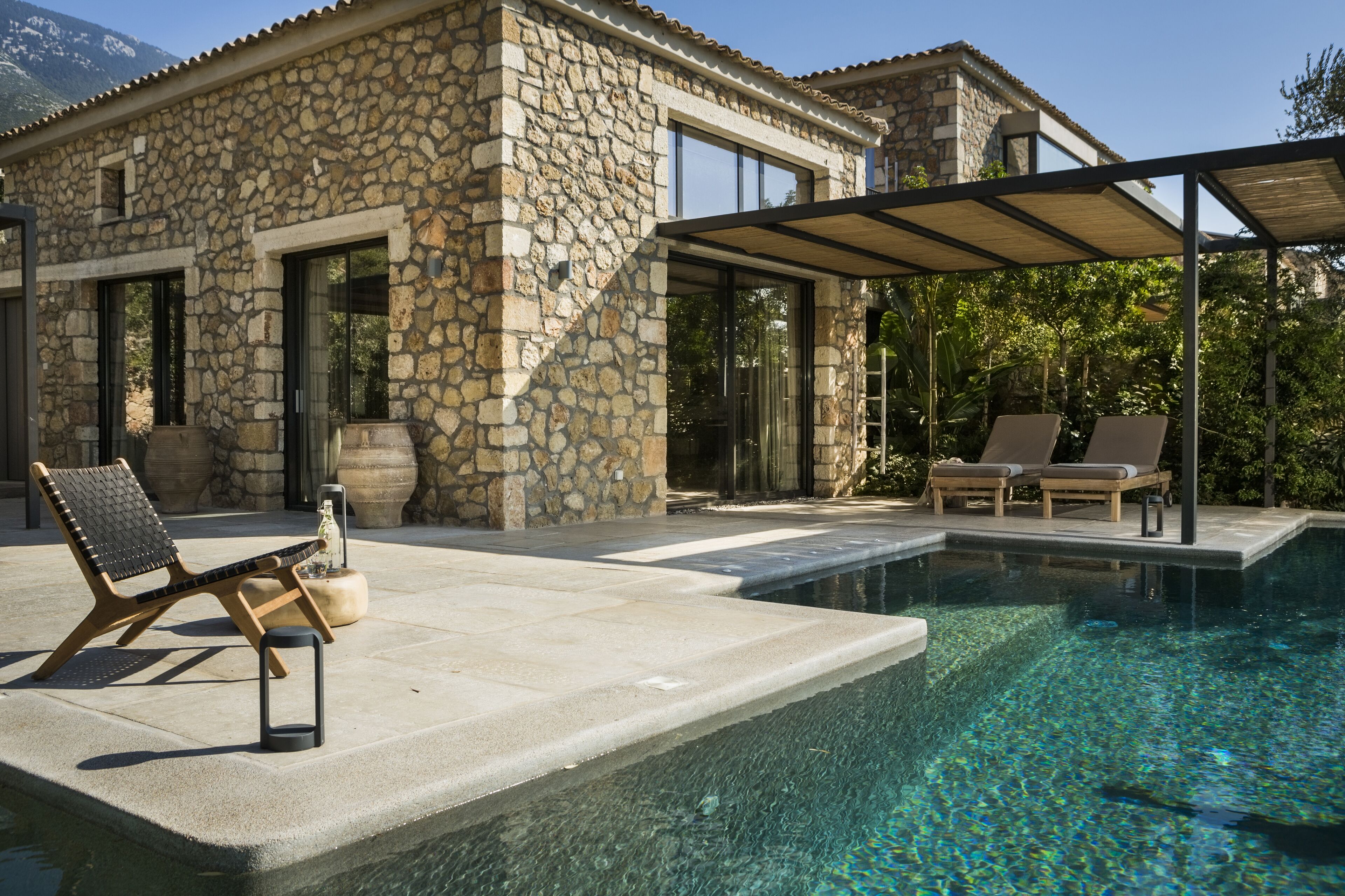 A stone building with a pool, outdoor seating, and a covered area.