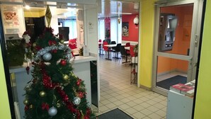 A hotel lobby with a Christmas tree, a reception desk, and a dining area. - Hotel du Triangle (Talange)