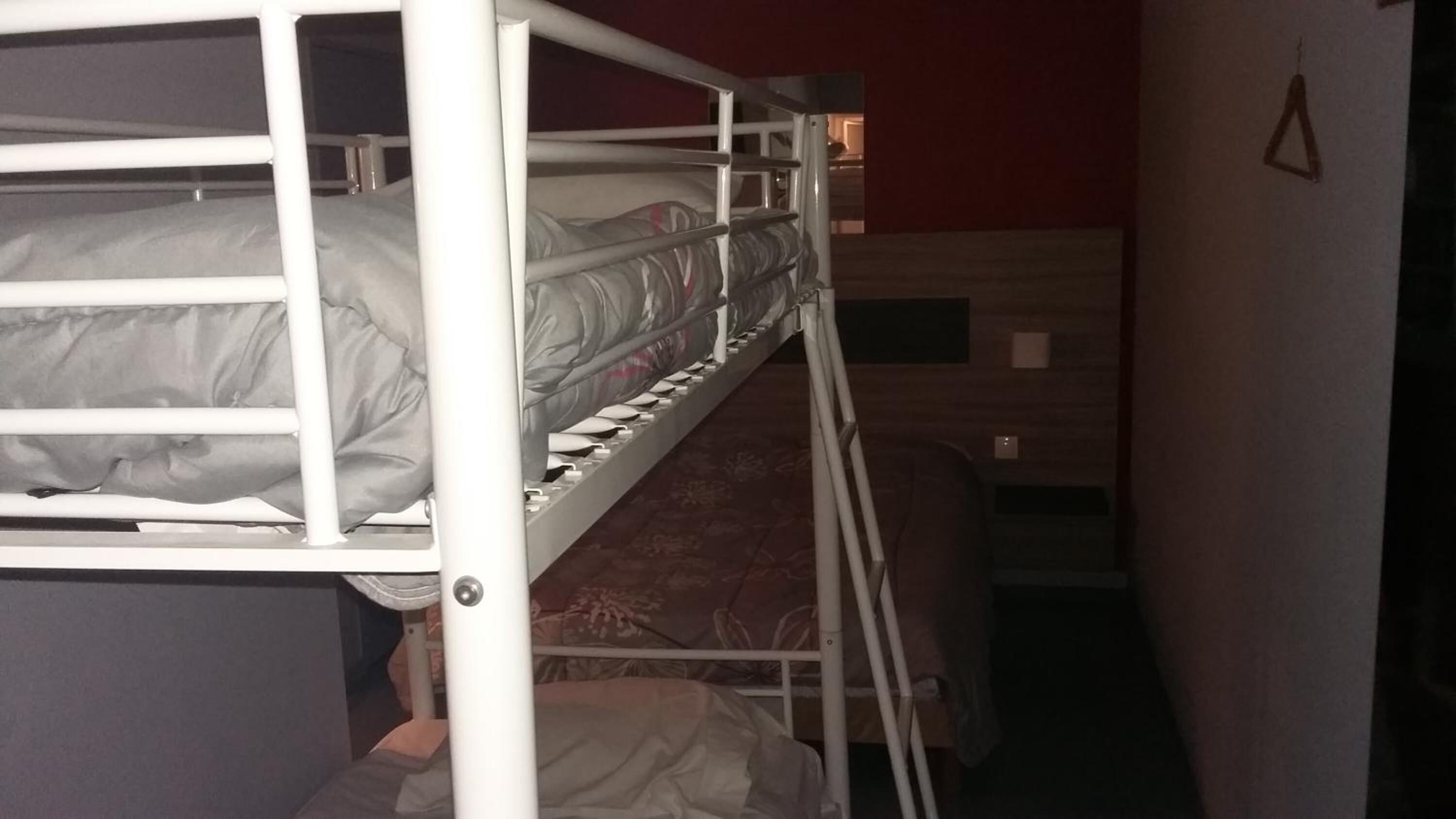 Ein Schlafraum mit Etagenbetten, einer roten Wand und einem kleinen Fenster.