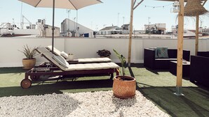 A rooftop terrace with a lounge area, a large umbrella, and potted plants. - The Boutike Guesthouse - Hostel (Seville)