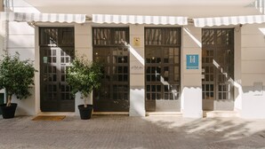 A building with large glass doors, a sign reading "Hôtel", and a staircase leading to an upper level. - The Boutike Guesthouse - Hostel (Seville)