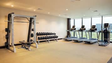 A gym with weightlifting equipment, treadmills, and dumbbells.