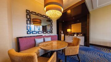 Un hall d’hôtel avec une table ronde, deux chaises, un canapé, un miroir décoratif et un lustre.