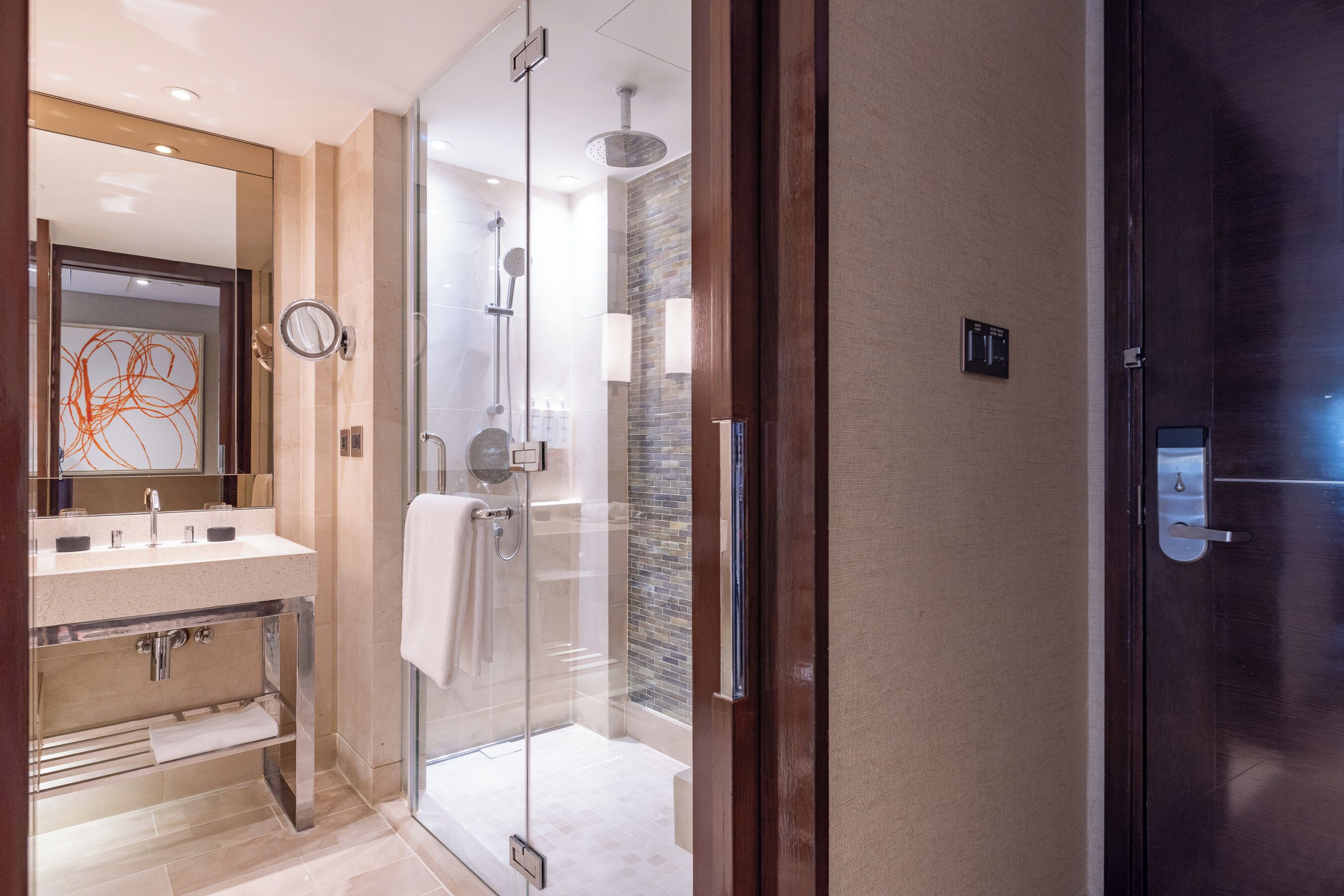 A modern bathroom with a glass-enclosed shower, a vanity with a mirror, and a towel rack.