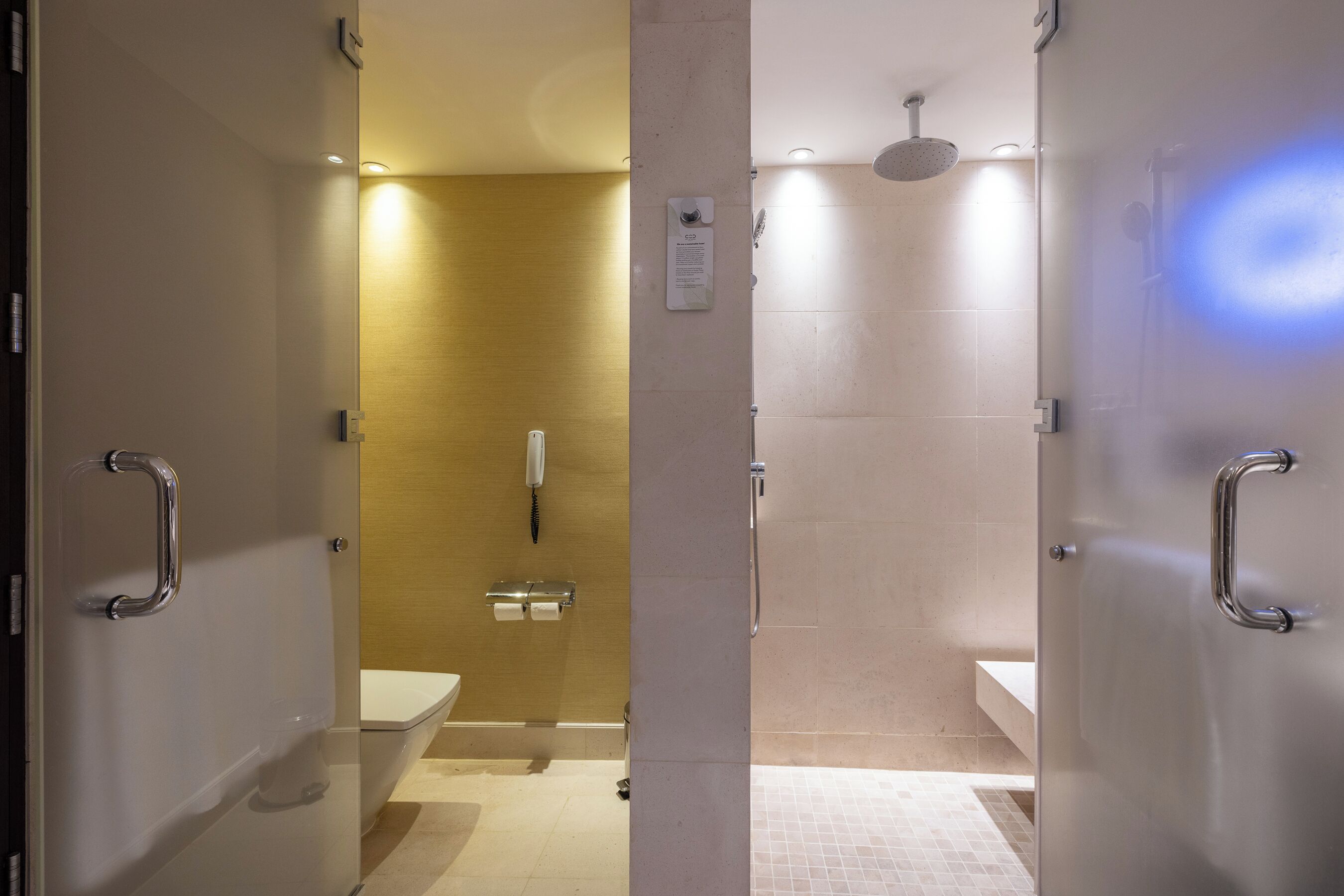 Un baño moderno con separador de vidrio, inodoro, zona de ducha y lavamanos.