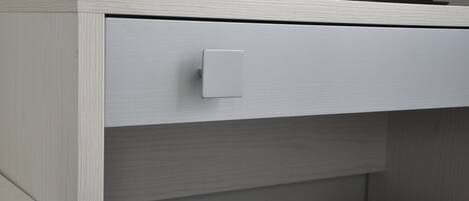 A white cabinet with a drawer, a light switch, and a black object on top.
