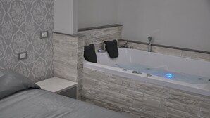 A modern bathroom with a stone wall, a bathtub, and a small bedside table.