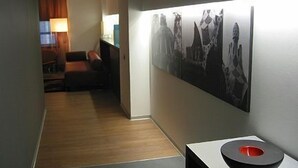 A hallway with a wooden floor, a black and white artwork on the wall, and a modern table with a red object on it.