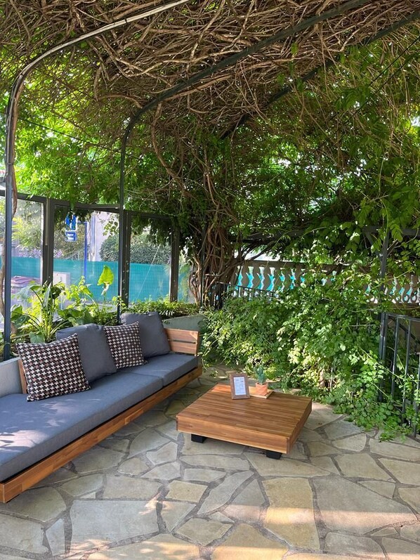 Un área de estar al aire libre con un banco de madera y un banco acolchado con cojines estampados.