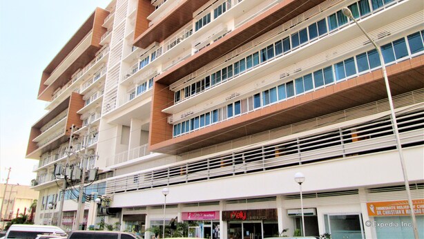 A multi-story building with balconies, a Burger & Pizza restaurant, and a sign for Dr. Christian V. Manco. - Primavera Residences (Cagayan de Oro)